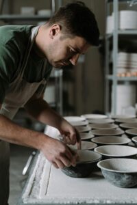 A skilled artisan focuses on making ceramic bowls in a pottery workshop, showcasing craftsmanship.